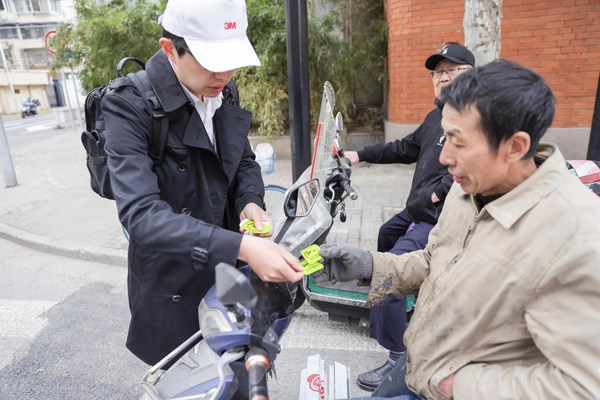 3M志愿者向过路的非机动车驾驶员赠送骑行反光贴
