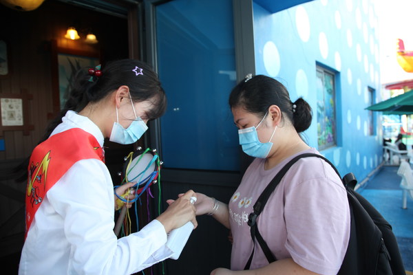 上海欢乐谷景区工作人员为游客进行手部消毒
