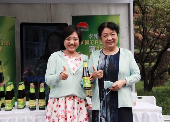 李锦记酱料集团中国区企业事务总监陈姝（左）向中国食品科学技术学会孟素荷理事长介绍本次展出的新品